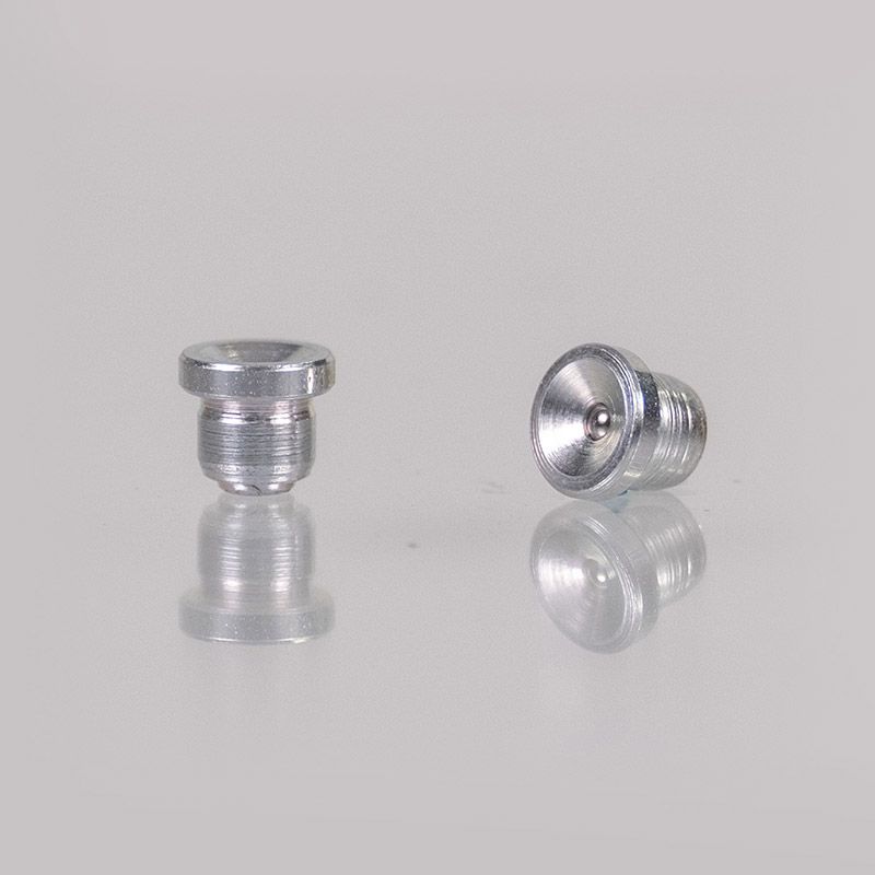 Zwei kleine Metallschrauben mit Gewinde an der Unterseite liegen auf einer reflektierenden Oberfläche. Eine steht aufrecht, die andere ist geneigt.