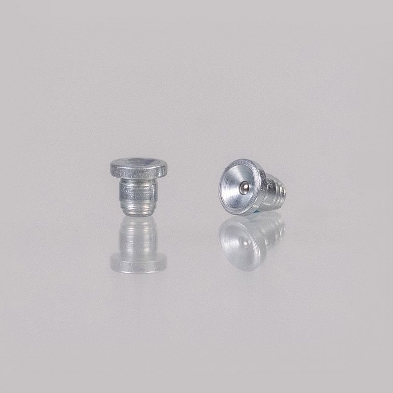 Zwei kleine silberne Metallnieten. Eine aufrecht, die andere auf der Seite, beide mit reflektierender Oberfläche.