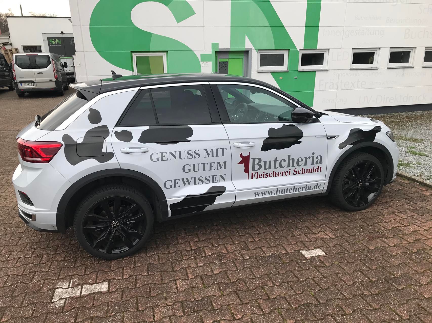 Ein weißes Auto mit schwarzen Flecken und Beschriftungen