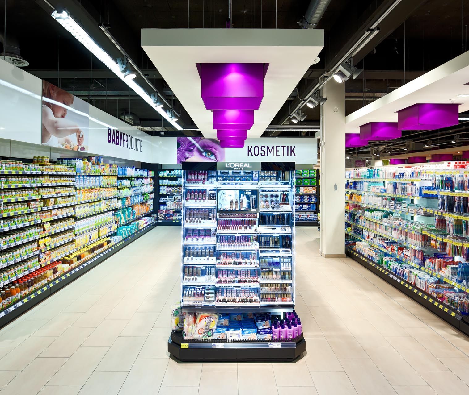 Objektgestaltung in einem großen Lebensmittelmarkt mit vielen Regalen und lila Lichtern.
