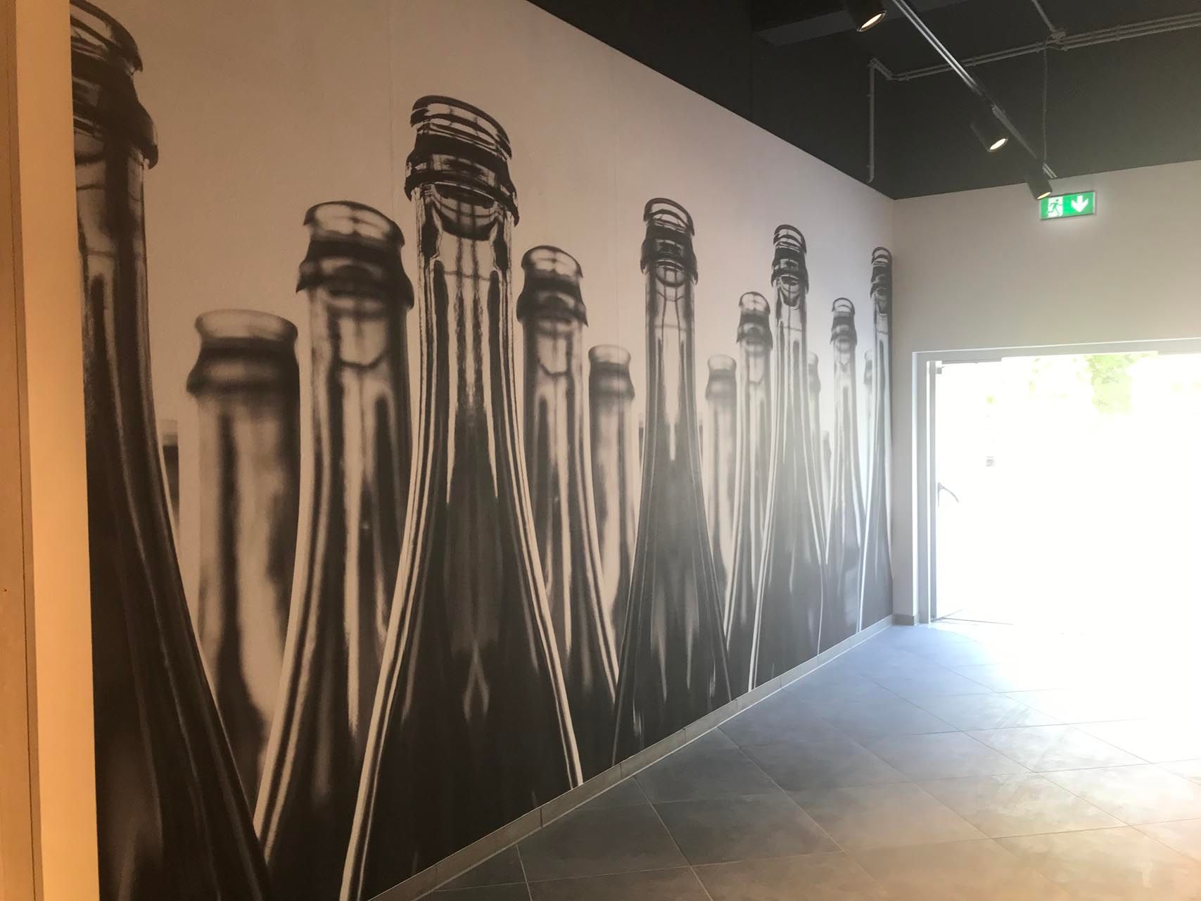 Eine Wand mit einer Reihe von Flaschen darauf.