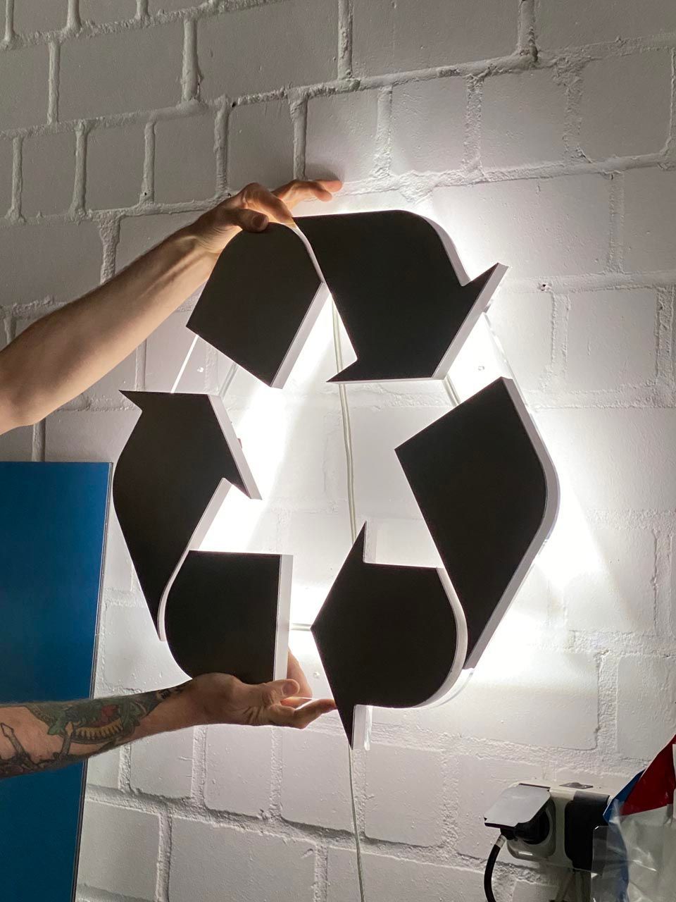 Eine Person hält ein schwarz-weißes Recyclingsymbol in ihren Händen.