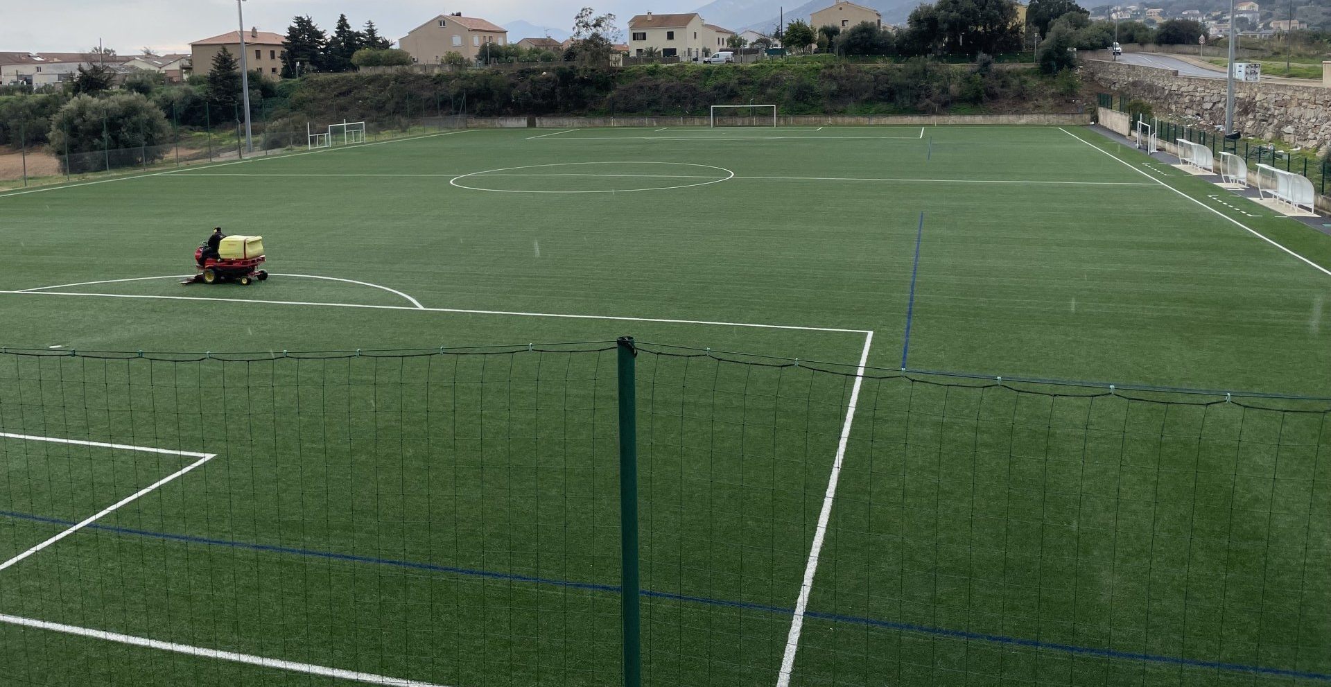 Gazon synthétique de terrain de foot en train d'être tondu