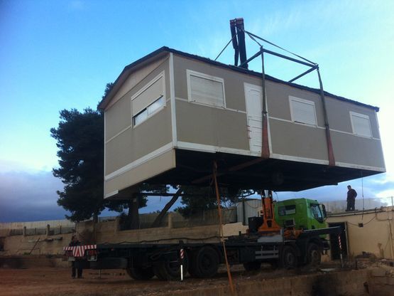 Una casa está siendo levantada por una grúa encima de un camión.