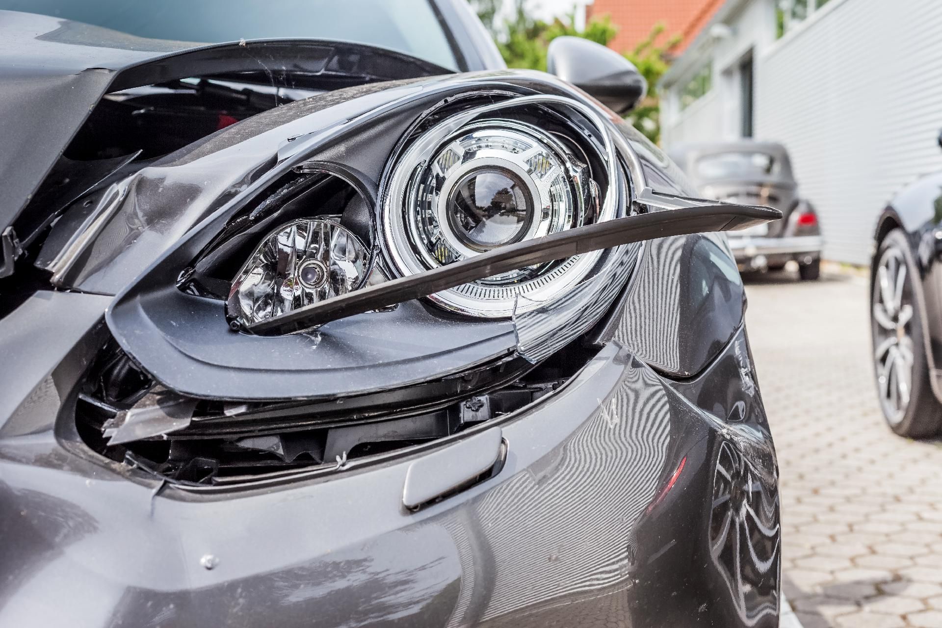 Beschädigter grauer Autoscheinwerfer, nach einem Zusammenstoß völlig zerstört.