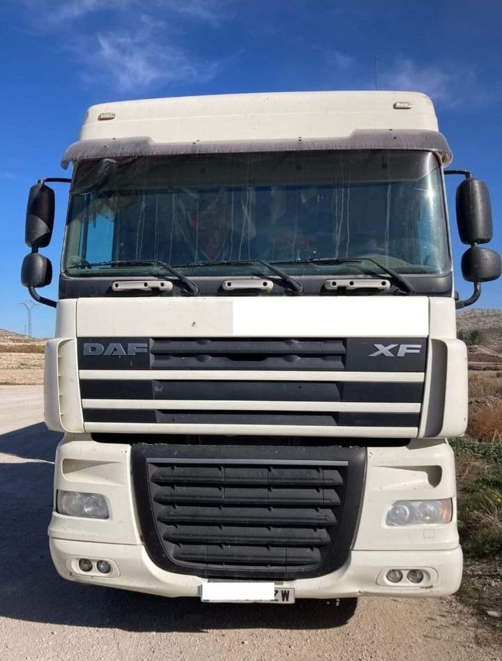 Un camión DAF blanco está estacionado al costado de un camino de tierra.