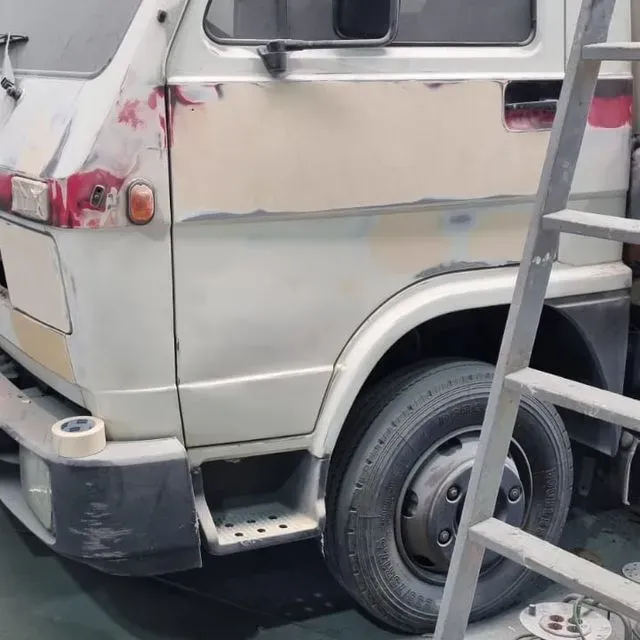 Una furgoneta blanca con una escalera apoyada en ella.