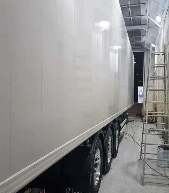Un camión blanco está estacionado en un garaje al lado de una escalera.