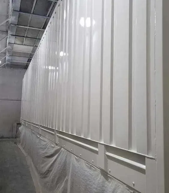 Una larga pared blanca en un almacén con techo.
