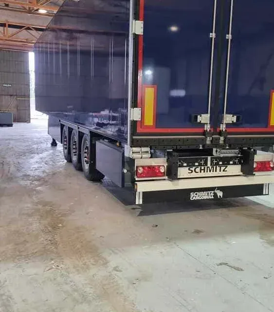 Un camión semirremolque Schmitz azul está estacionado en un garaje.
