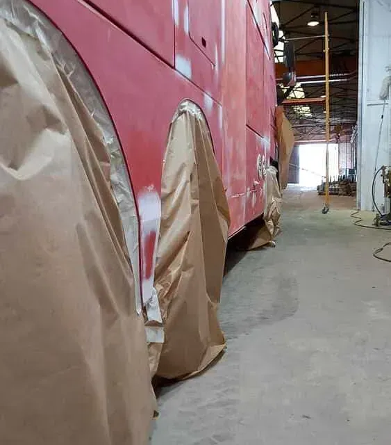 Se está pintando un autobús rojo en un garaje.