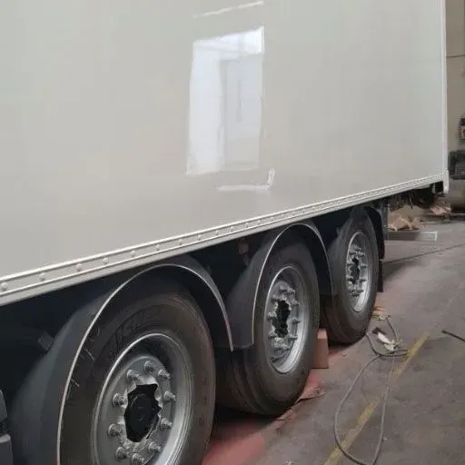 Un camión blanco con tres neumáticos está estacionado en un garaje.