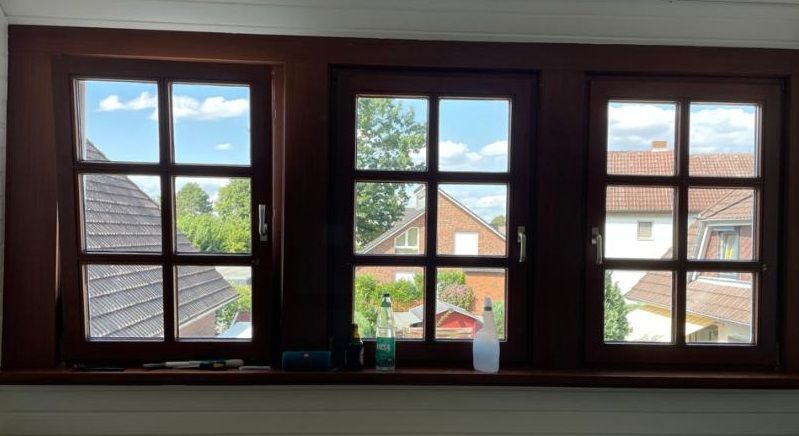 Drei Holzfenster mit Blick auf ein Haus .