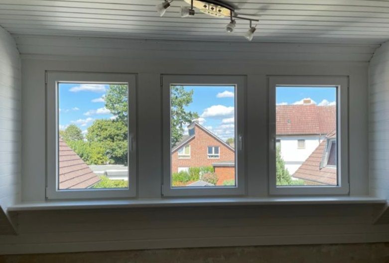 ein Raum mit drei Fenstern und einem Blick auf ein Haus .