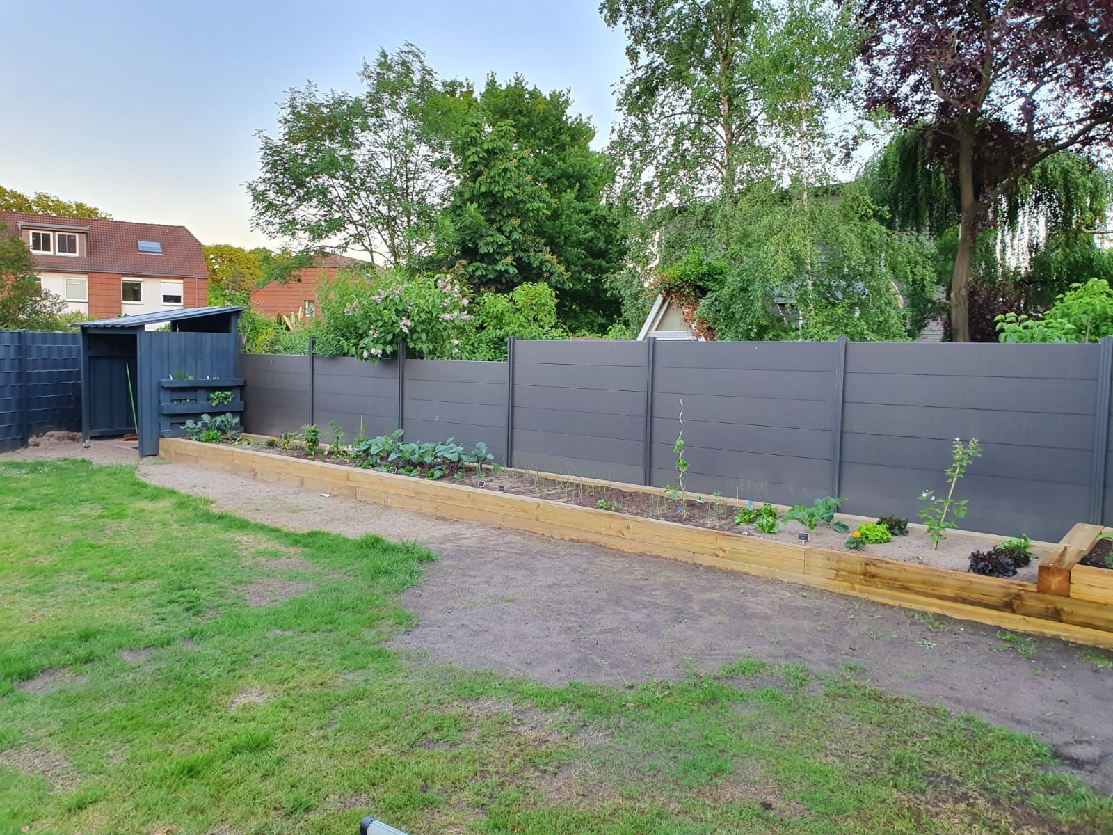 ein Garten mit einem Zaun und einem Hochbeet