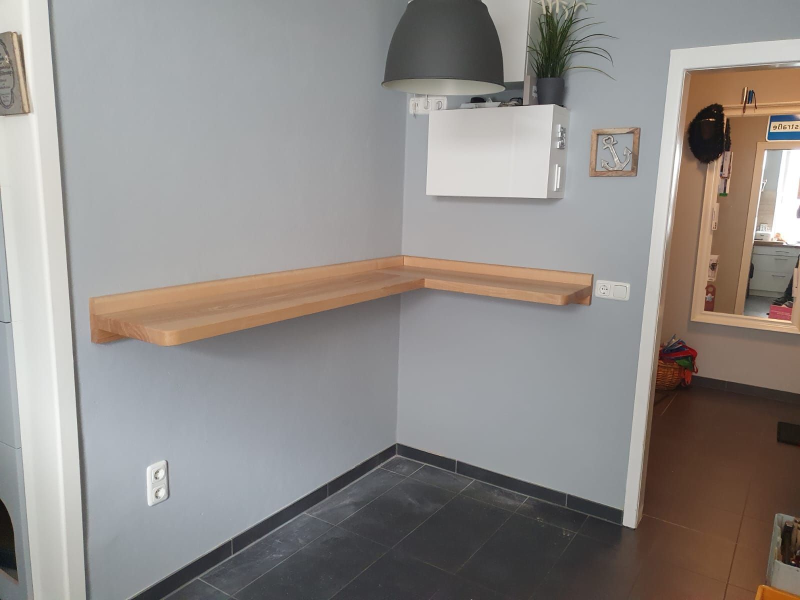 eine graue Wand mit einem weißen Regal darauf