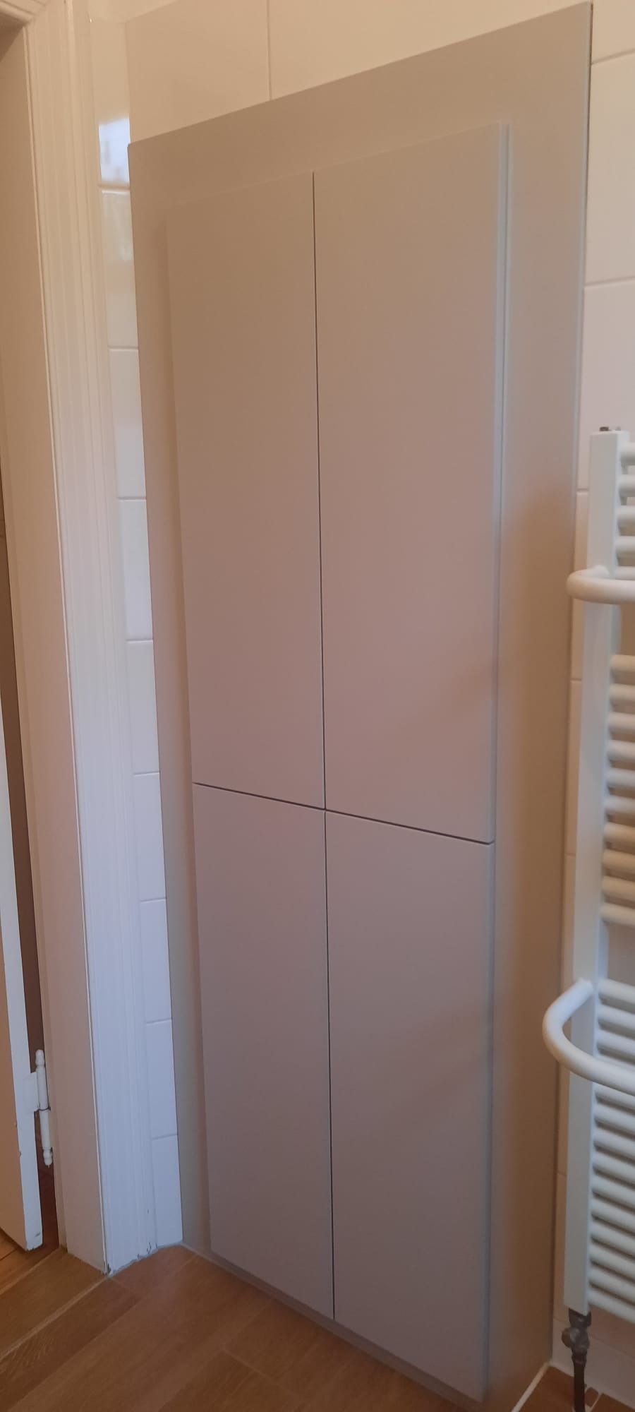 ein weißer schrank in einem badezimmer neben einem heizkörper