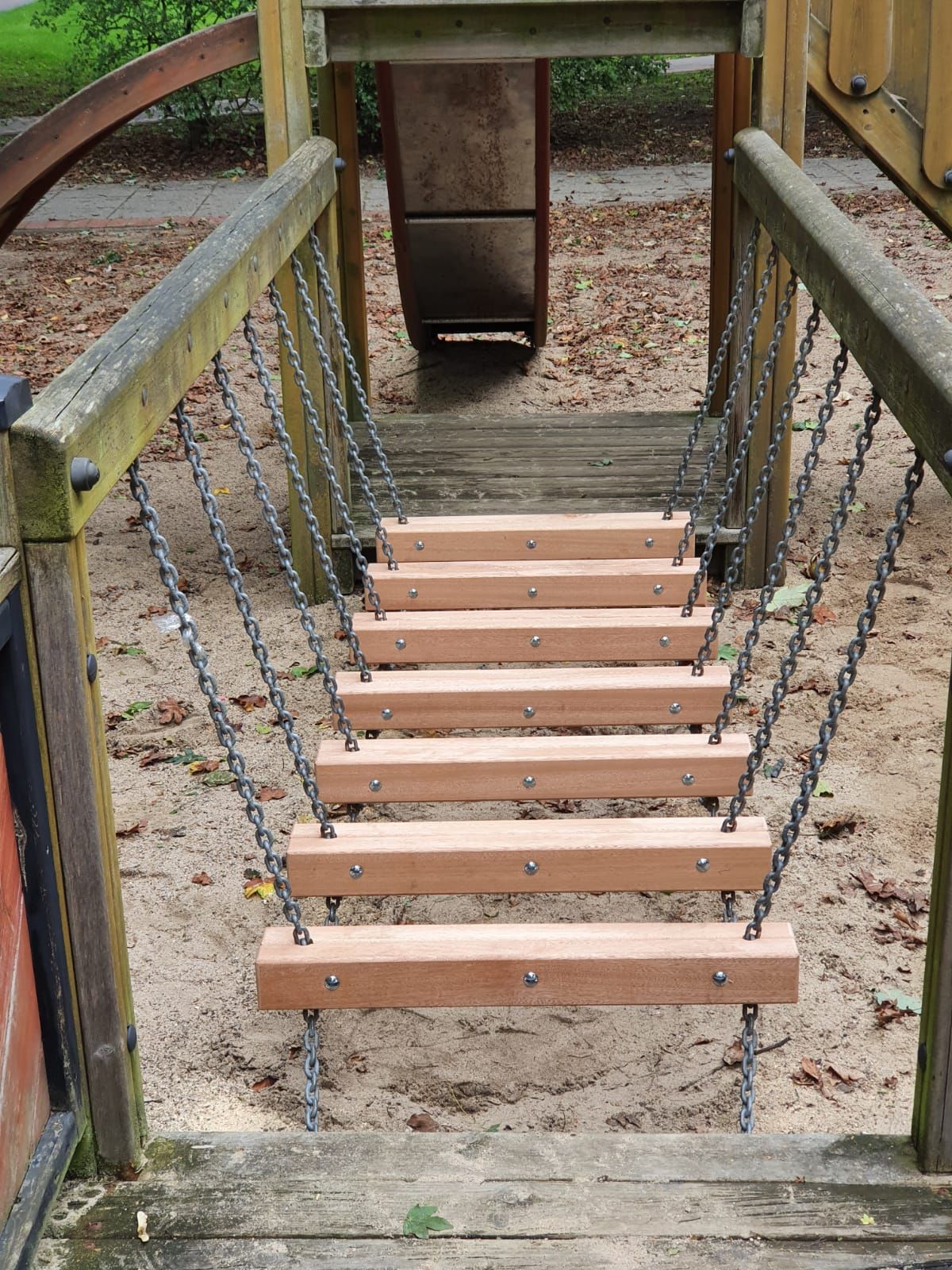 eine Holztreppe mit Ketten an einem Spielplatz