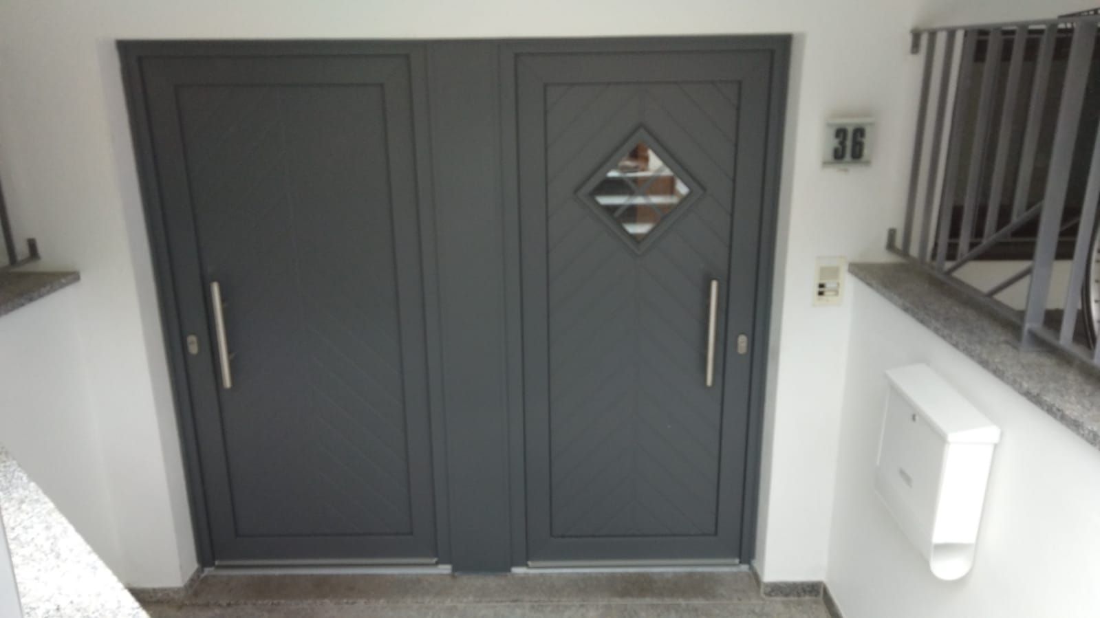 eine graue Haustür mit der Nummer 36 darauf