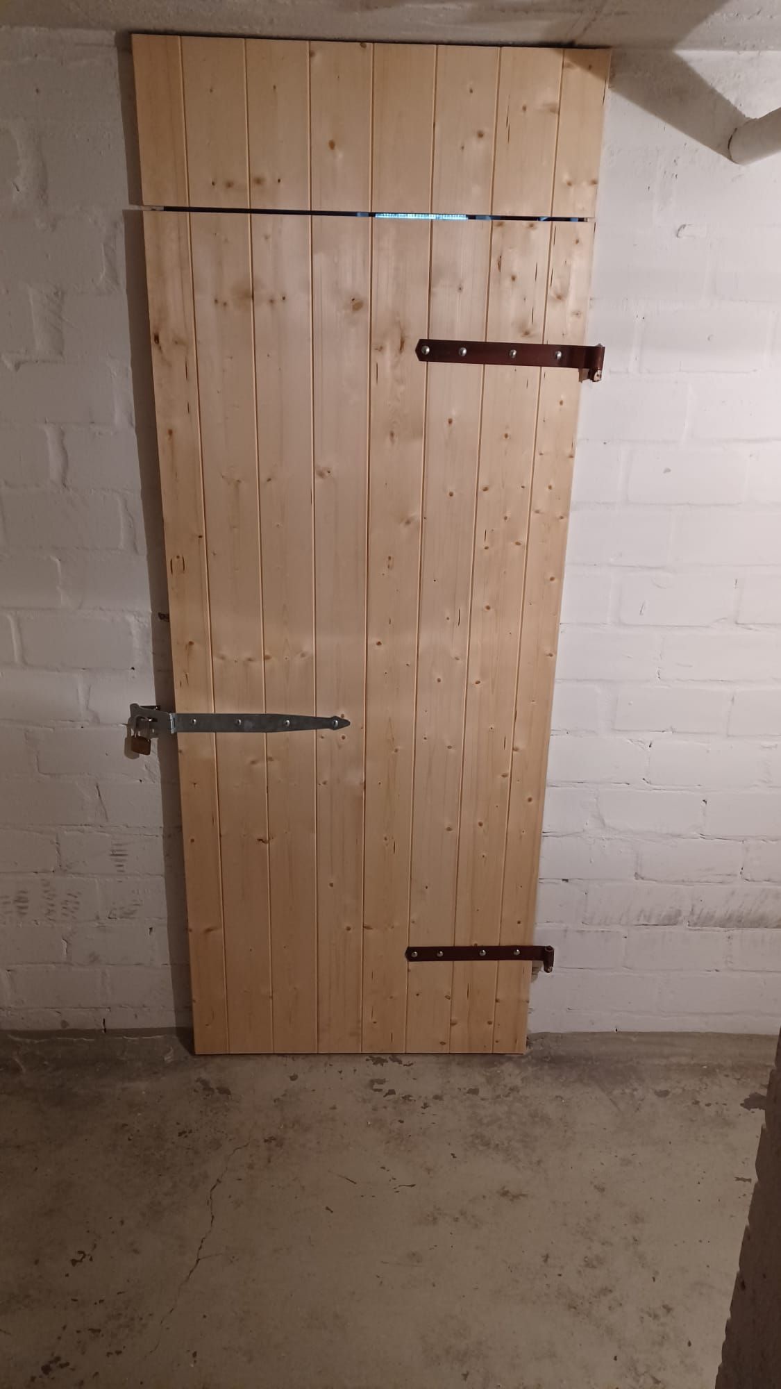 eine Holztür in einem Raum mit einer weißen Backsteinmauer