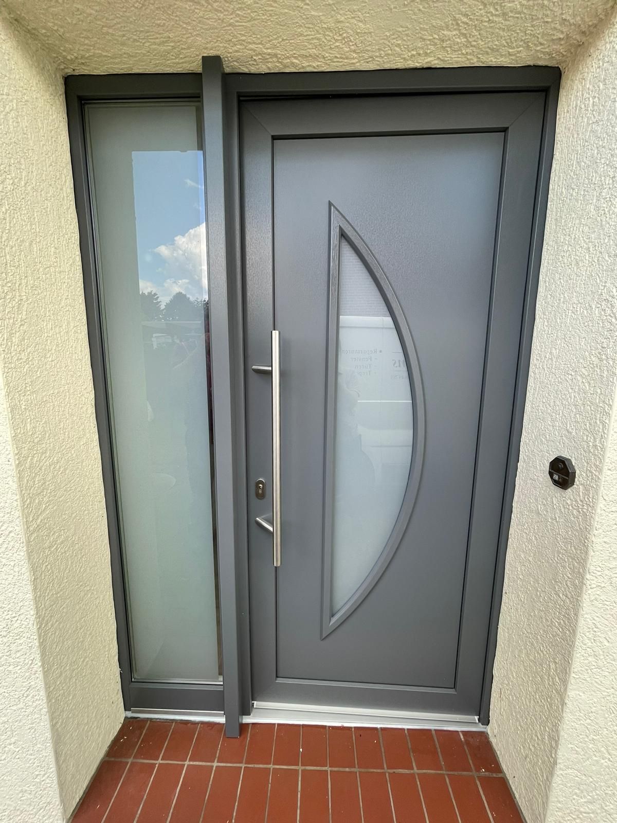 eine graue Haustür mit einem halbkreisförmigen Fenster