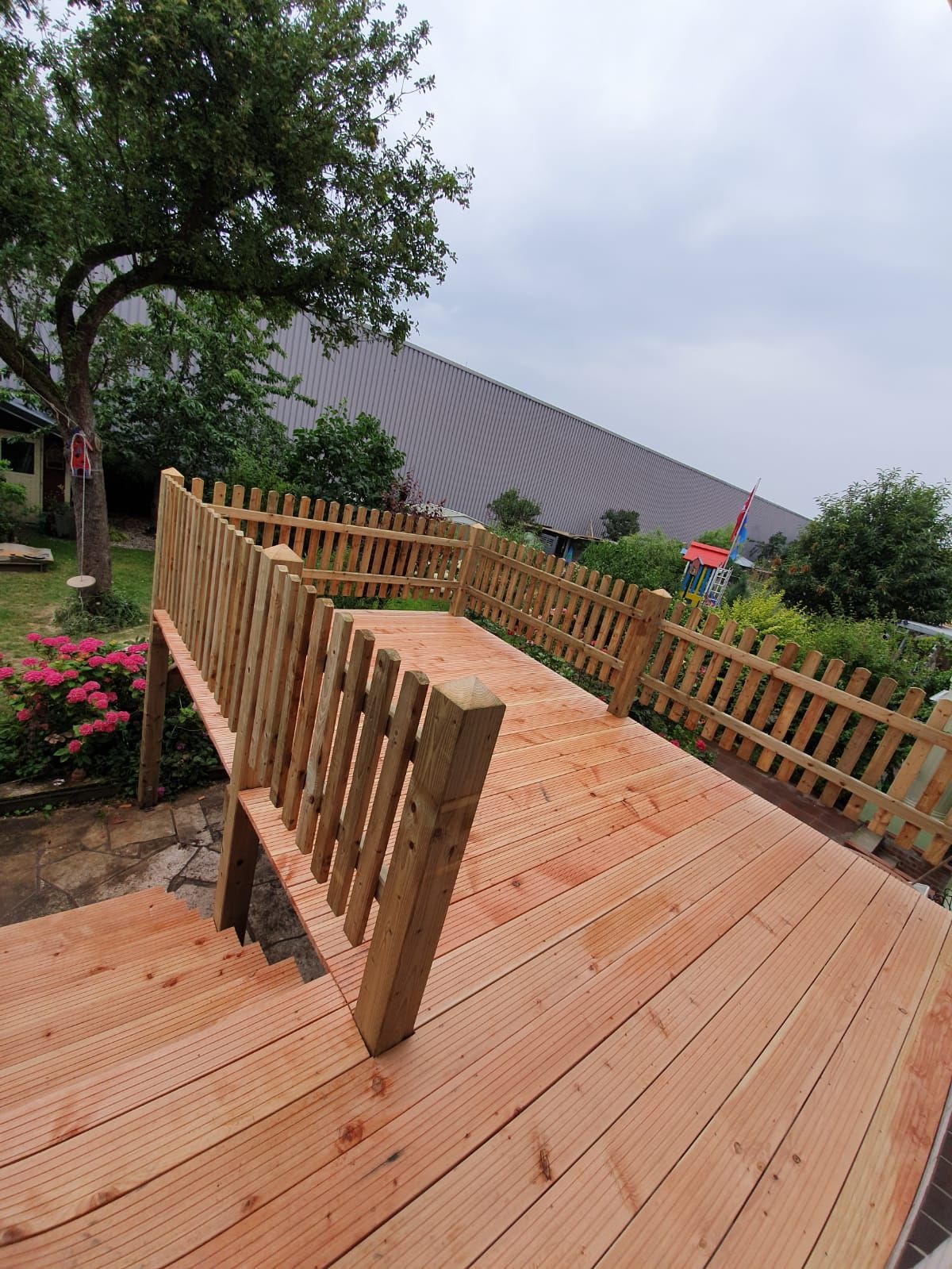 ein Holzdeck mit einem Zaun dahinter