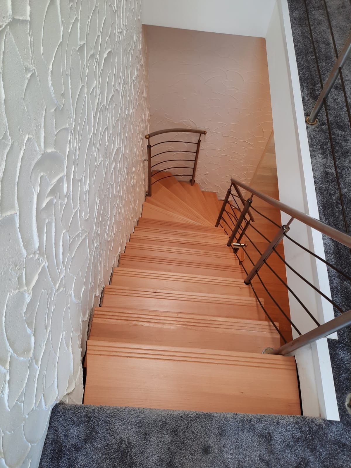 eine Holztreppe mit einem Metallgeländer und einer weißen Wand