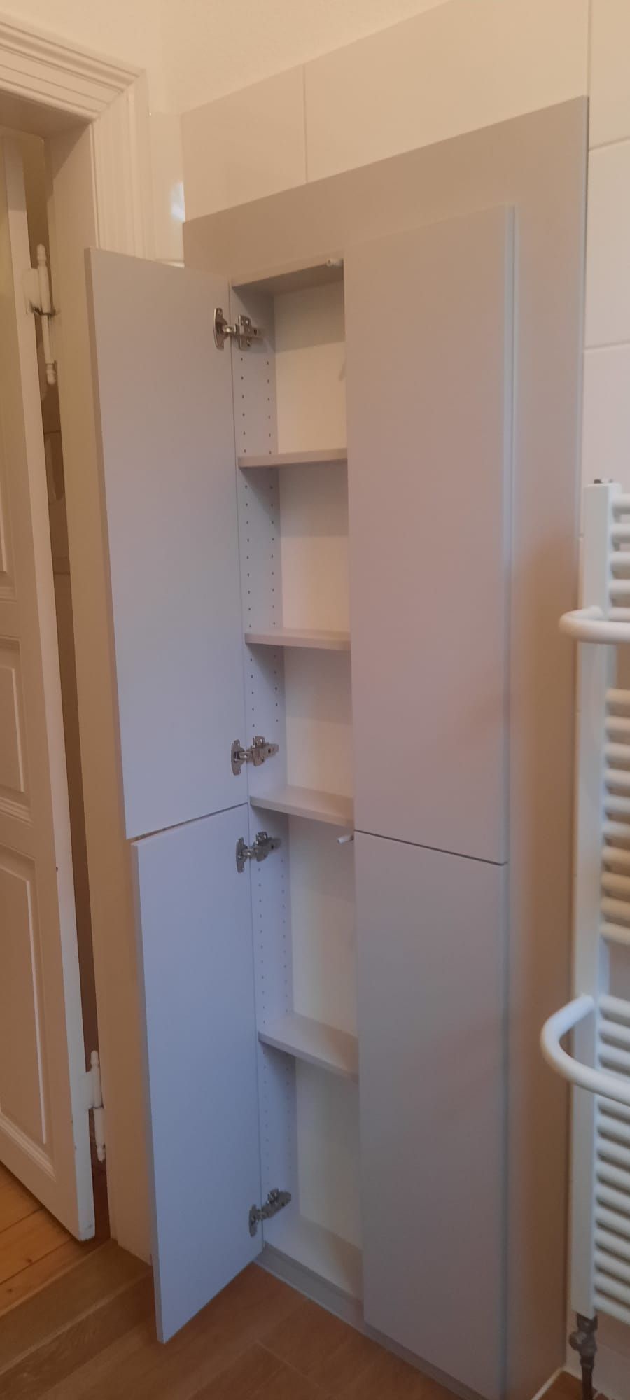 ein Badezimmerschrank mit offenen Türen und Regalen