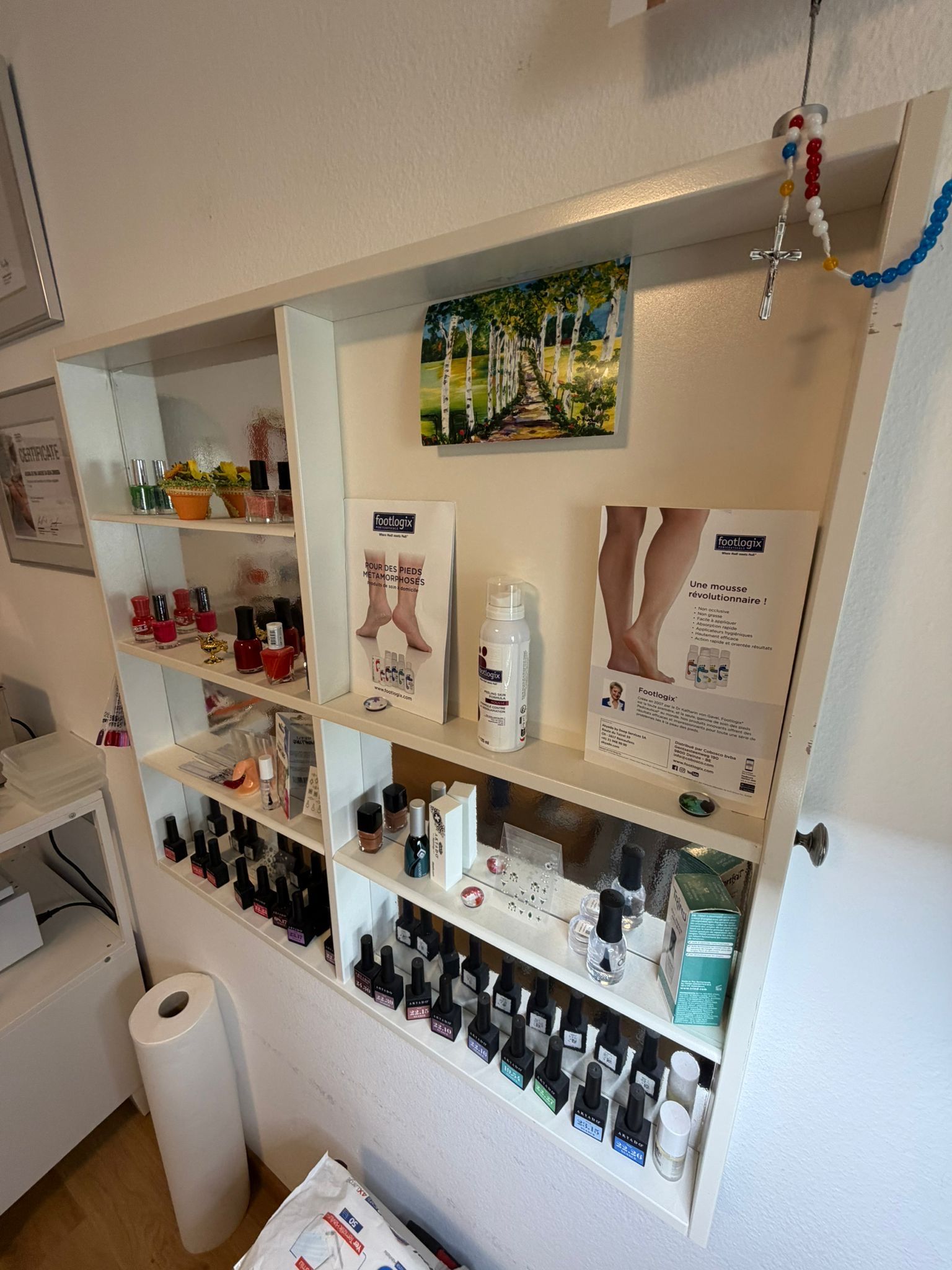 Étagères murales de salon présentant des produits de beauté, des affiches et une poubelle blanche.