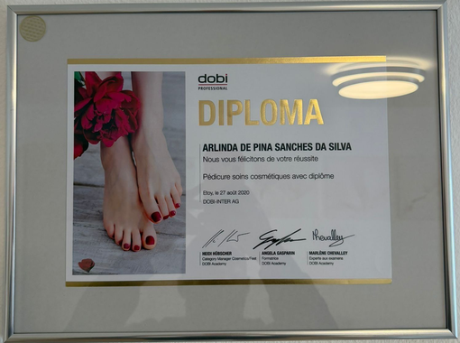 Diplôme encadré avec une photo de pieds peints en rouge et de fleurs rouges sur la gauche.