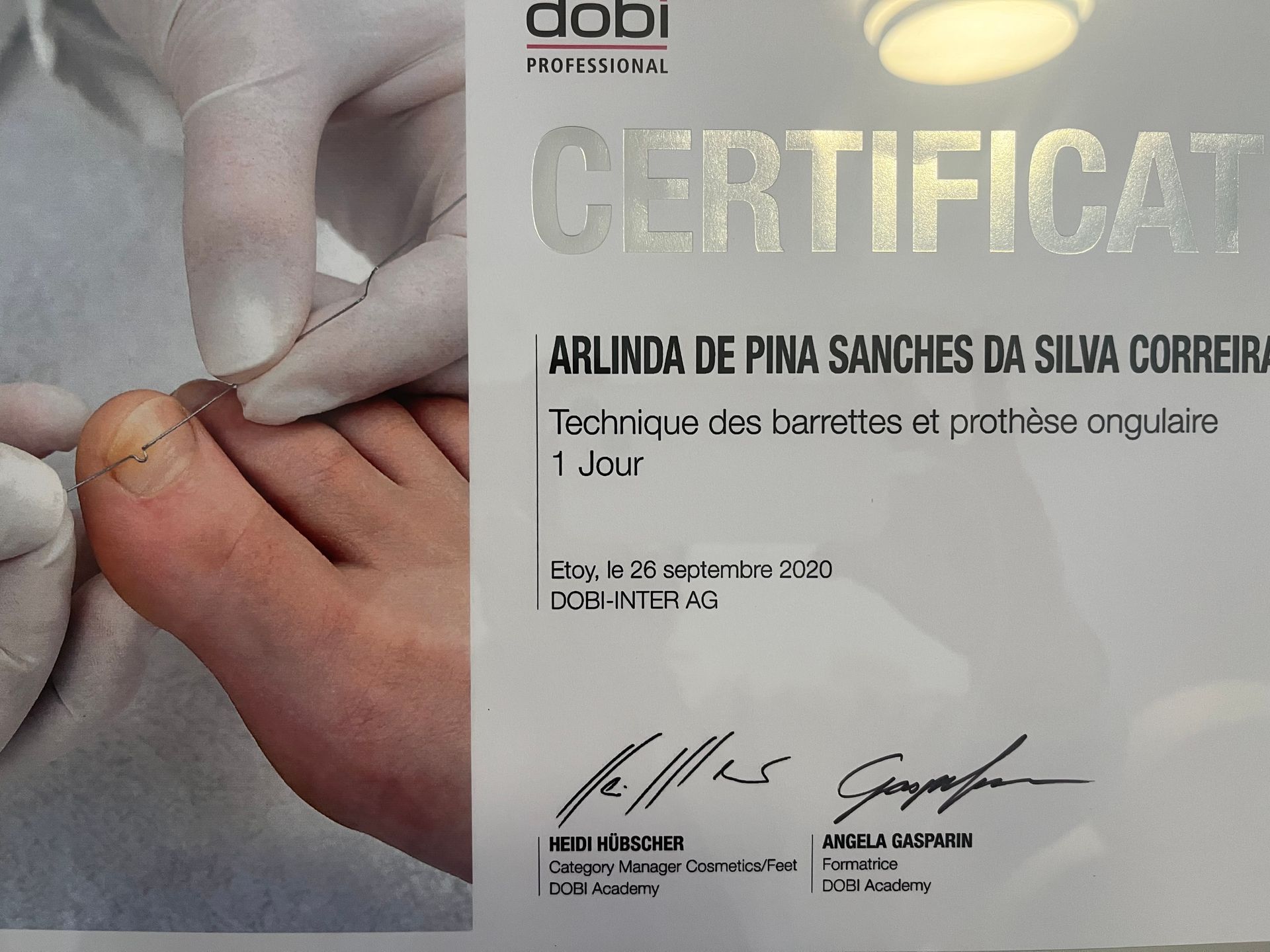 Main tenant un certificat avec la mention « CERTIFICAT » en gros caractères et une signature imprimée en bas.