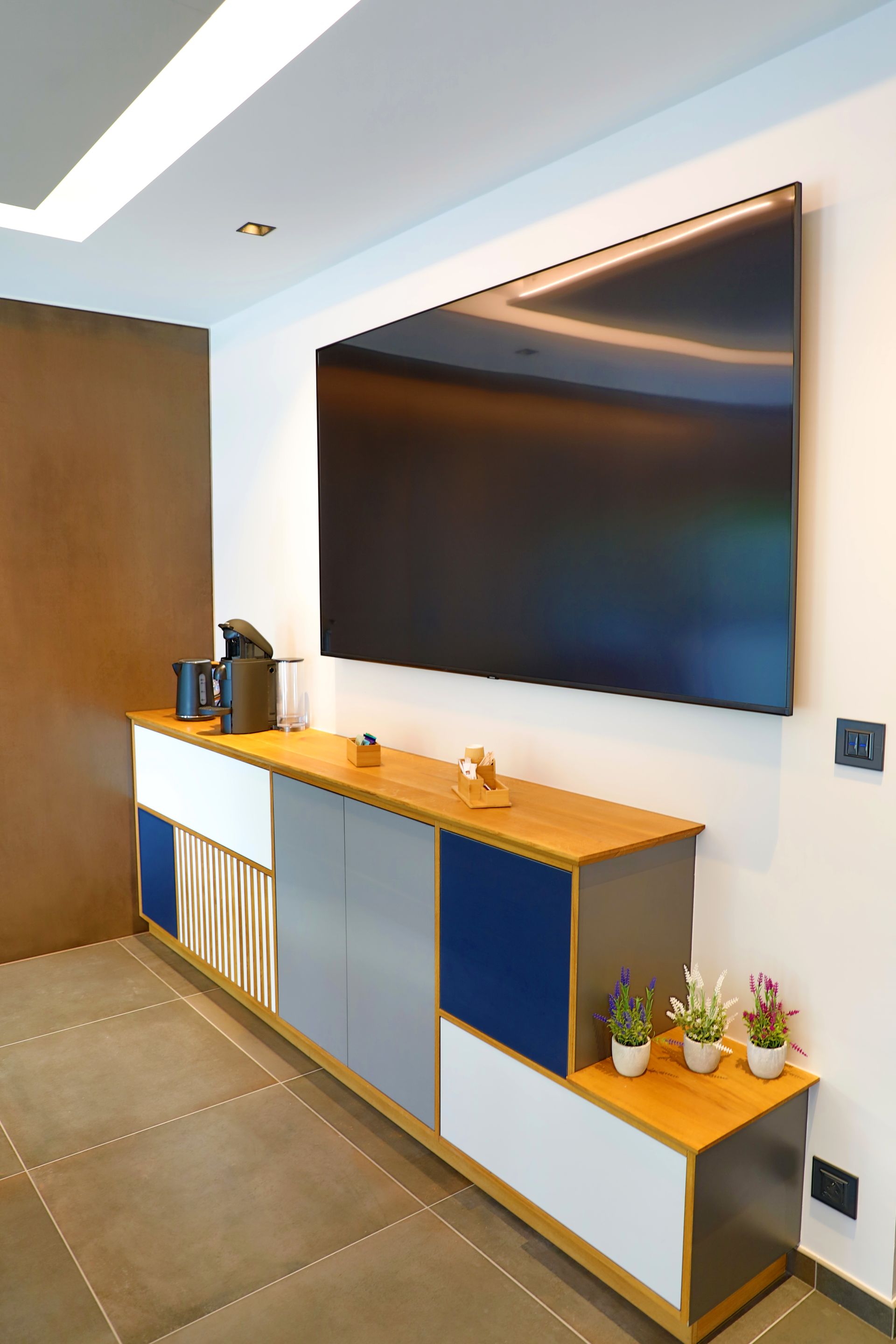 Meuble de télévision sur mesure avec façade bleue, blanche et grise, plusieurs rangements et décorations