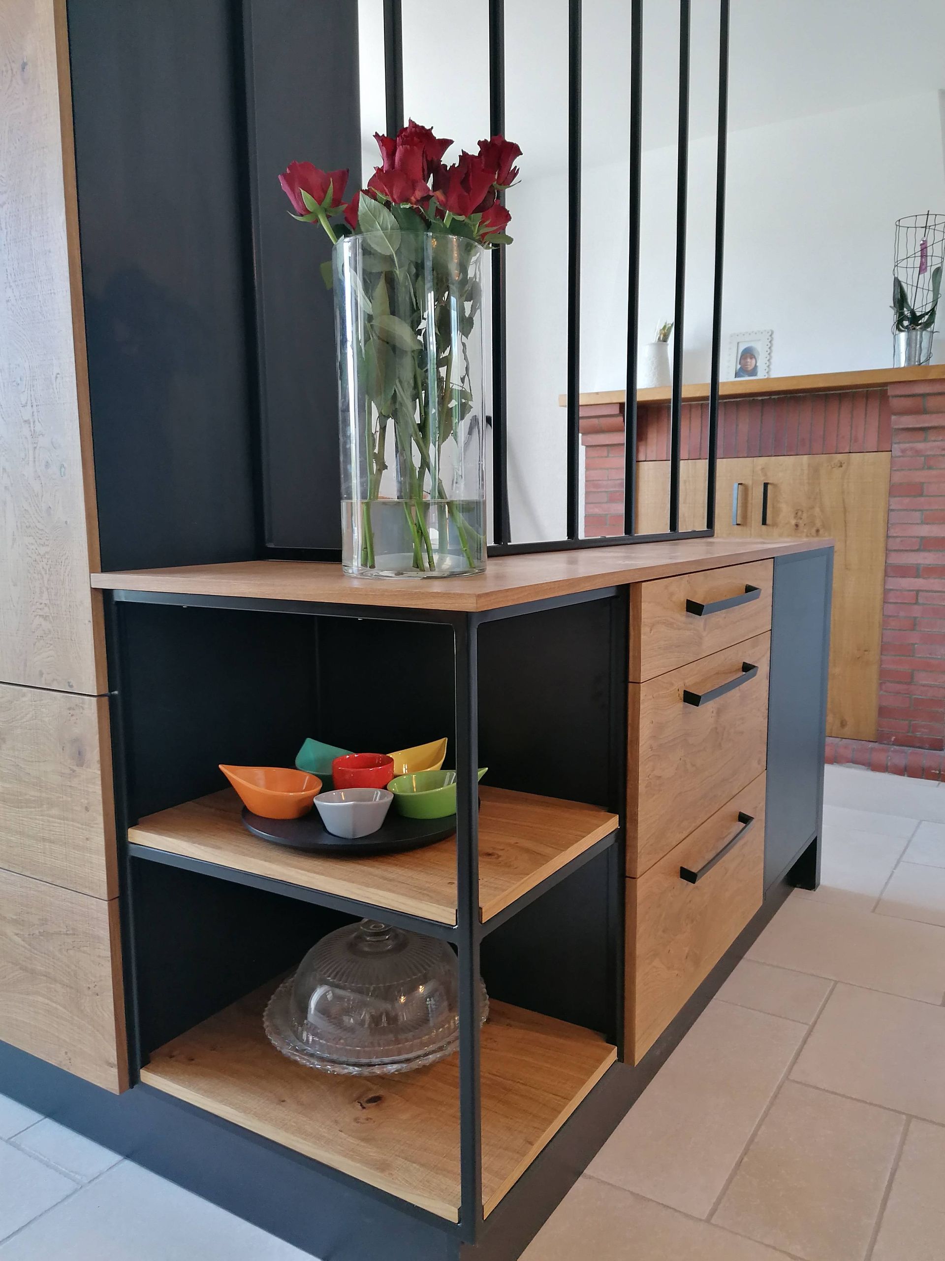 Meuble de rangement noir et boisé avec étagères ouvertes, plusieurs tiroirs et une verrière sur la partie supérieure