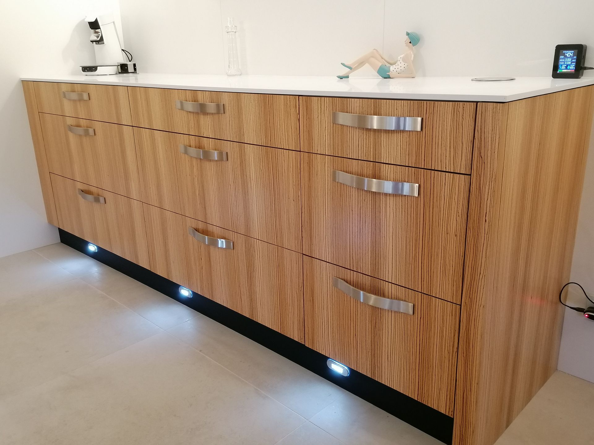 Meubles de cuisine esprit bois zébrano et corian blanc, avec plusieurs tiroirs