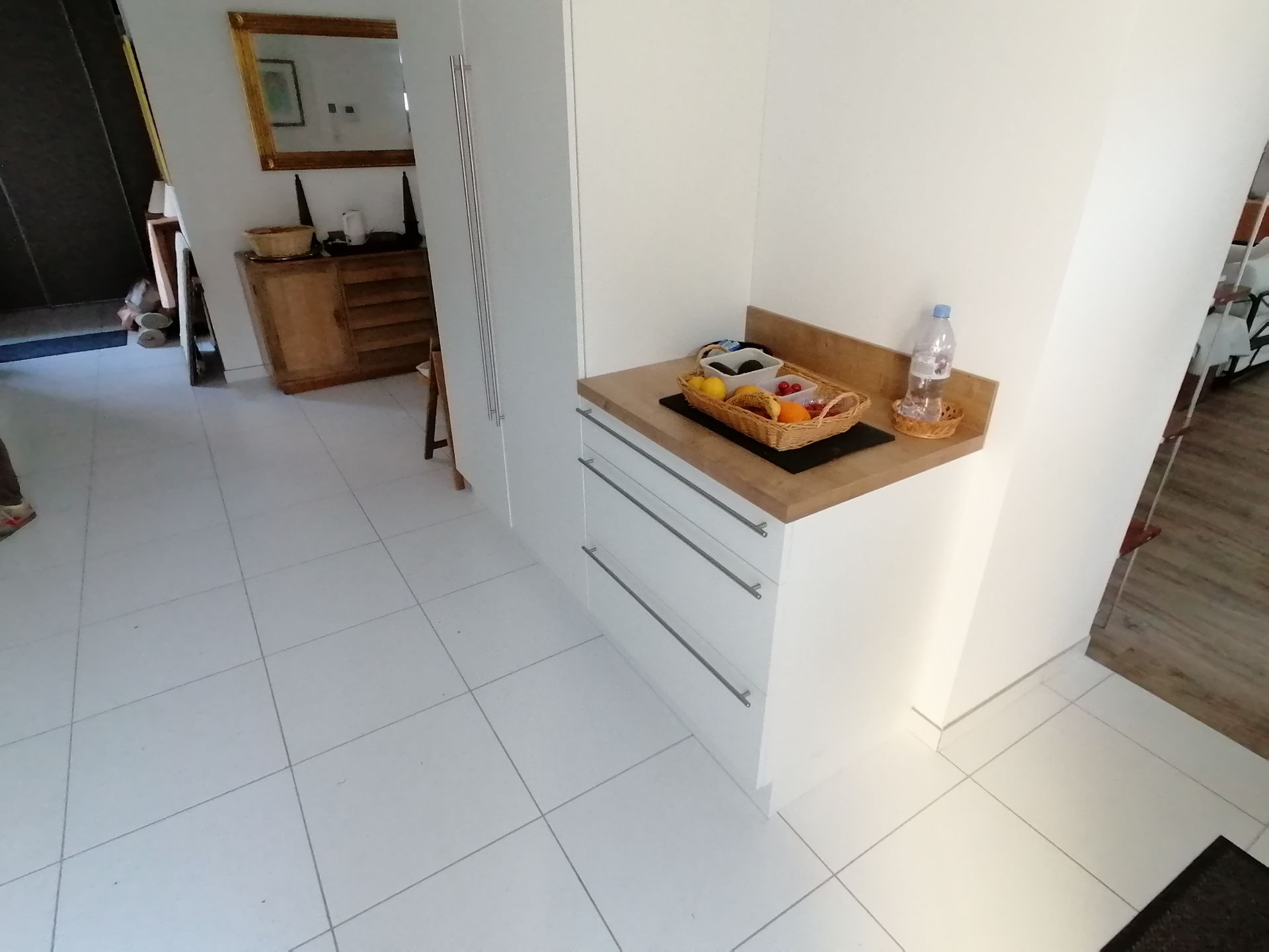 Espace de rangements sur mesure avec deux meubles blancs : un long en hauteur et un autre avec des tiroirs et avec un plan de travail boisé