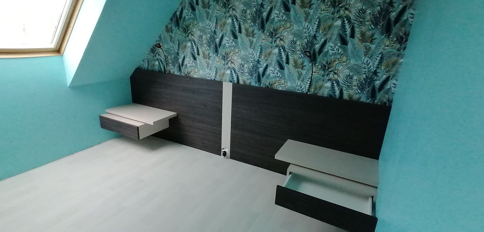 Tables de nuit et tête de lit avec prise de courant installées dans une chambre aux murs vert forêt et avec une tapisserie végétalisée