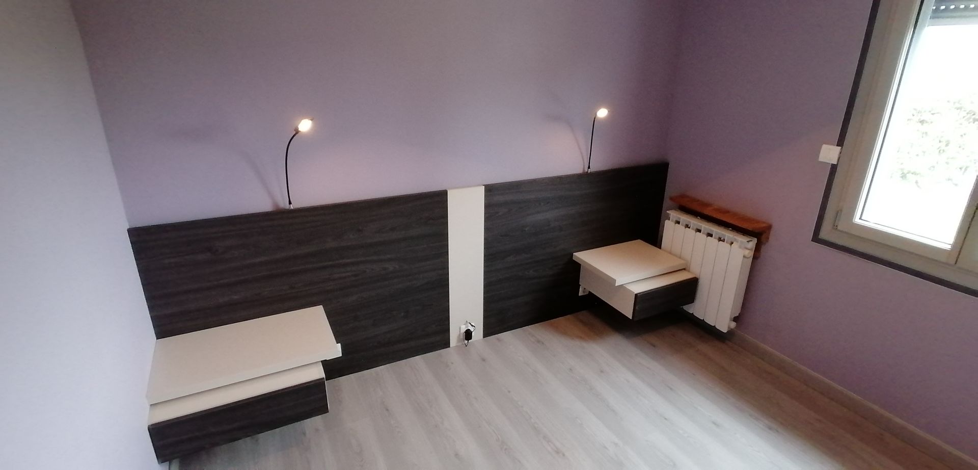 Tables de nuit et tête de lit avec prise de courant installées dans une chambre aux murs violets