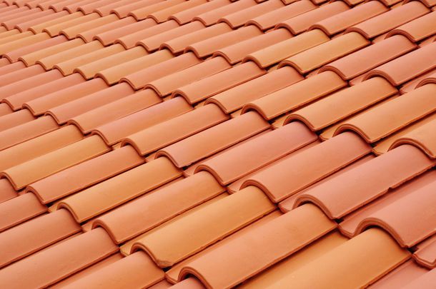 Des rangées de tuiles de toit en terre cuite orange qui se chevauchent.