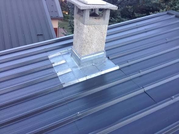 Toiture métallique avec cheminée et solins contre les toitures voisines.
