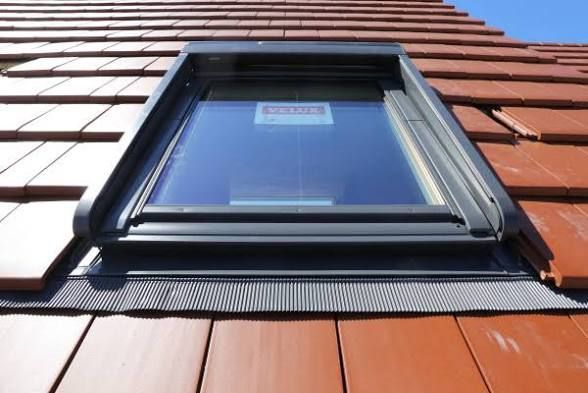Fenêtre de toit Velux sur un toit en tuiles en terre cuite rouge, vue d'en bas.