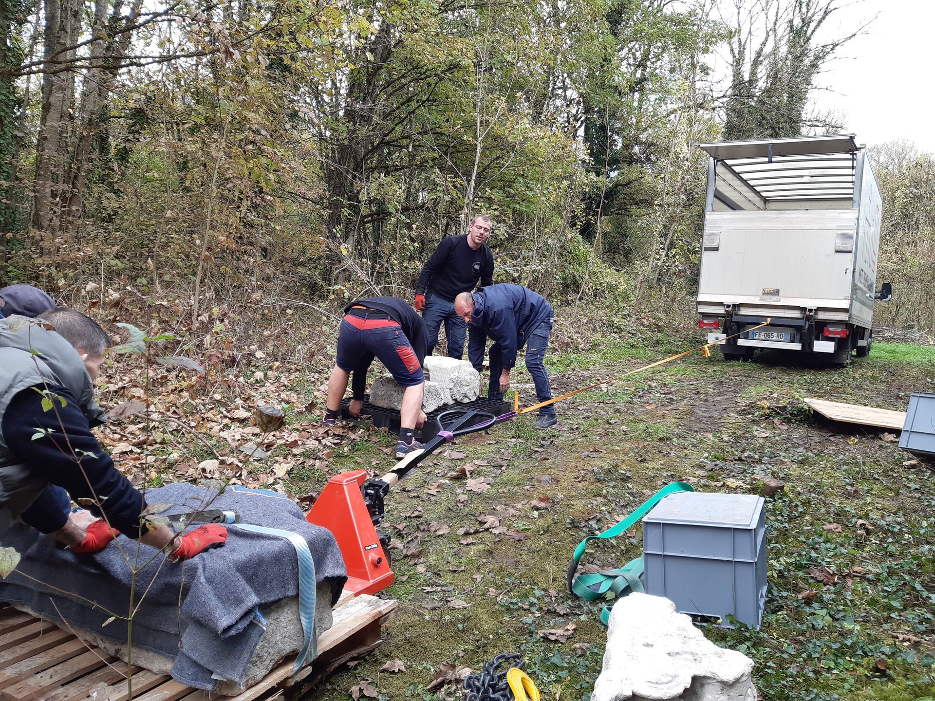 Trois homme qui essaie de porté une pierre.