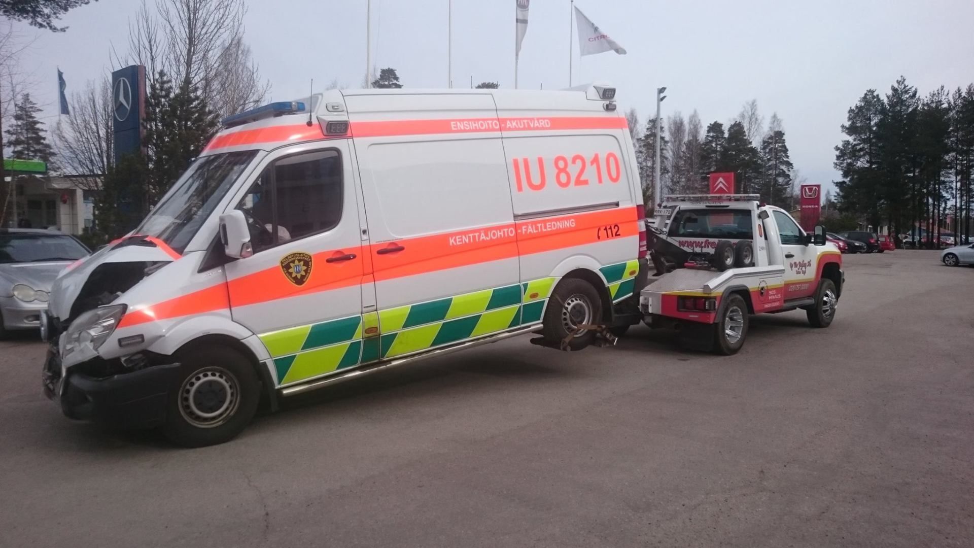 Ambulanssi ja pelastusauto pysäköitynä ulkona vierekkäin harmaana päivänä