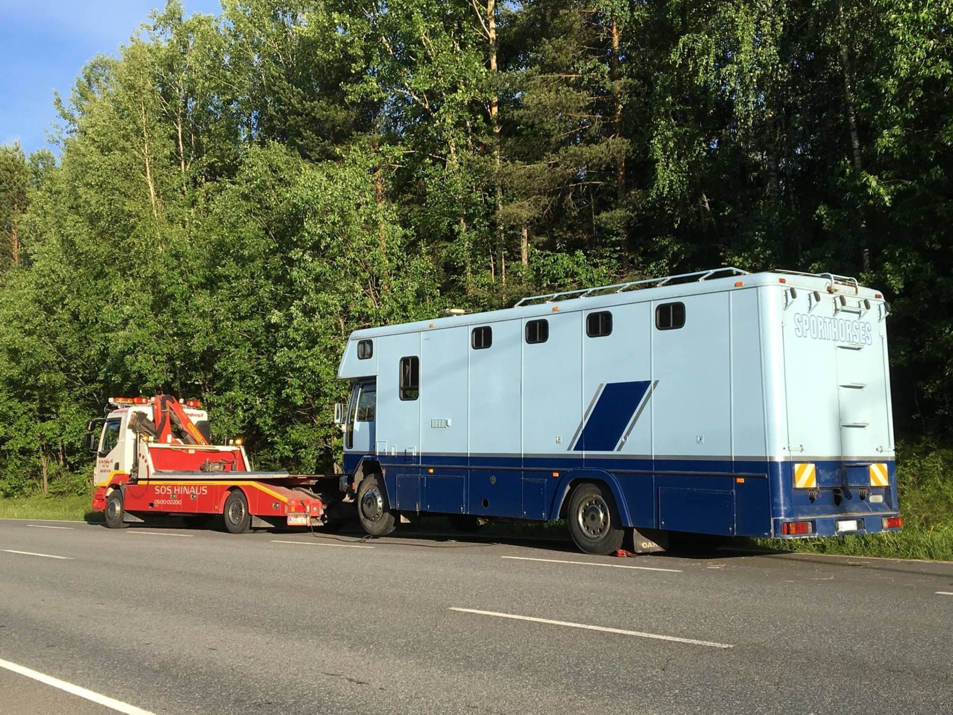Hinausauto hinausautossa sinistä huoltoautoa tien varrella puiden vieressä