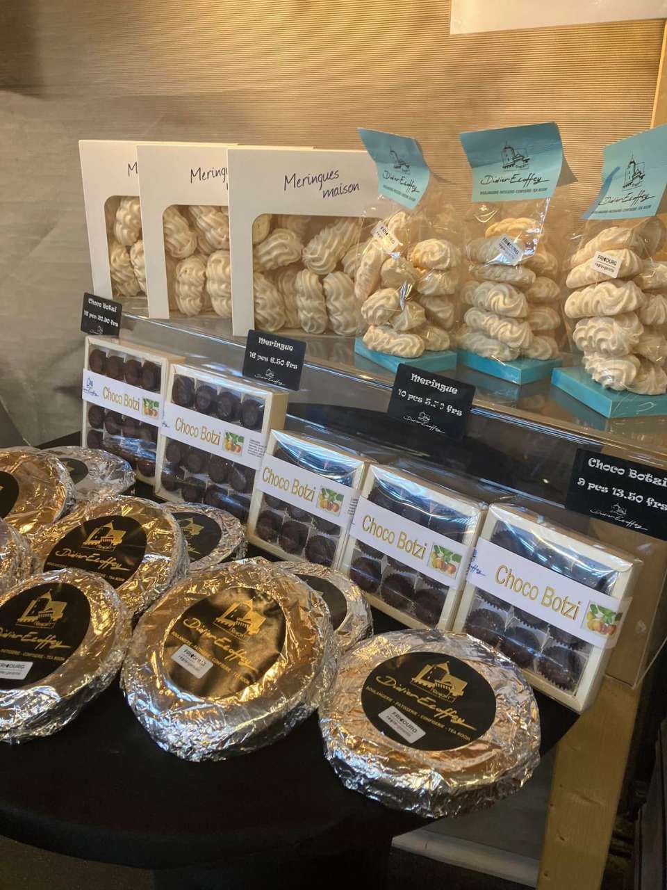 Une table présentant un assortiment de collations emballées, notamment des friandises de type meringue blanche et des bonbons enrobés de chocolat noir.