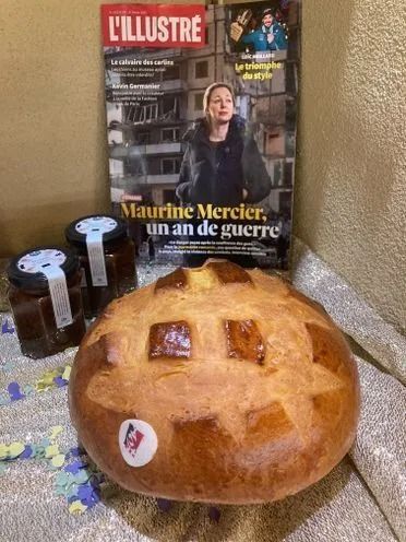 Un comptoir de boulangerie présente des étagères de pain frais et une vitrine remplie de viennoiseries, tartes et autres douceurs assorties.