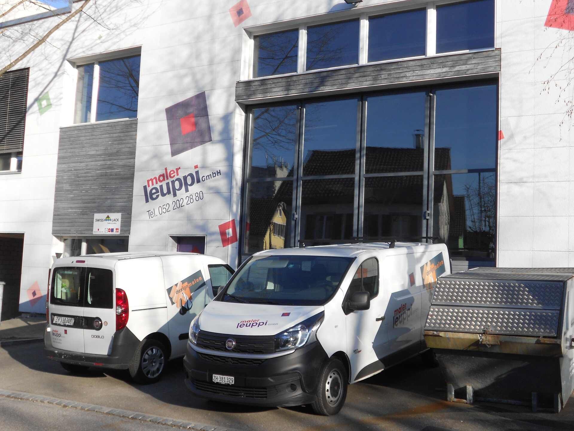 Zwei weisse Lieferwagen stehen vor dem Gebäude der Maler Leuppi GmbH.