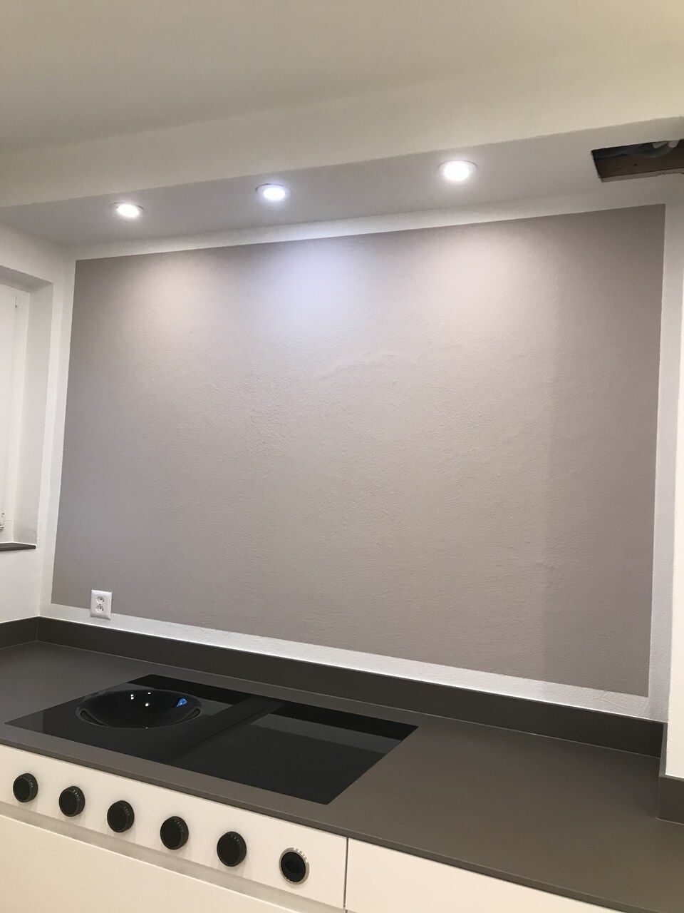 Eine Küche mit einem Herd mit Backofen und einer grossen Wand dahinter. Foto von der Maler Leuppi GmbH