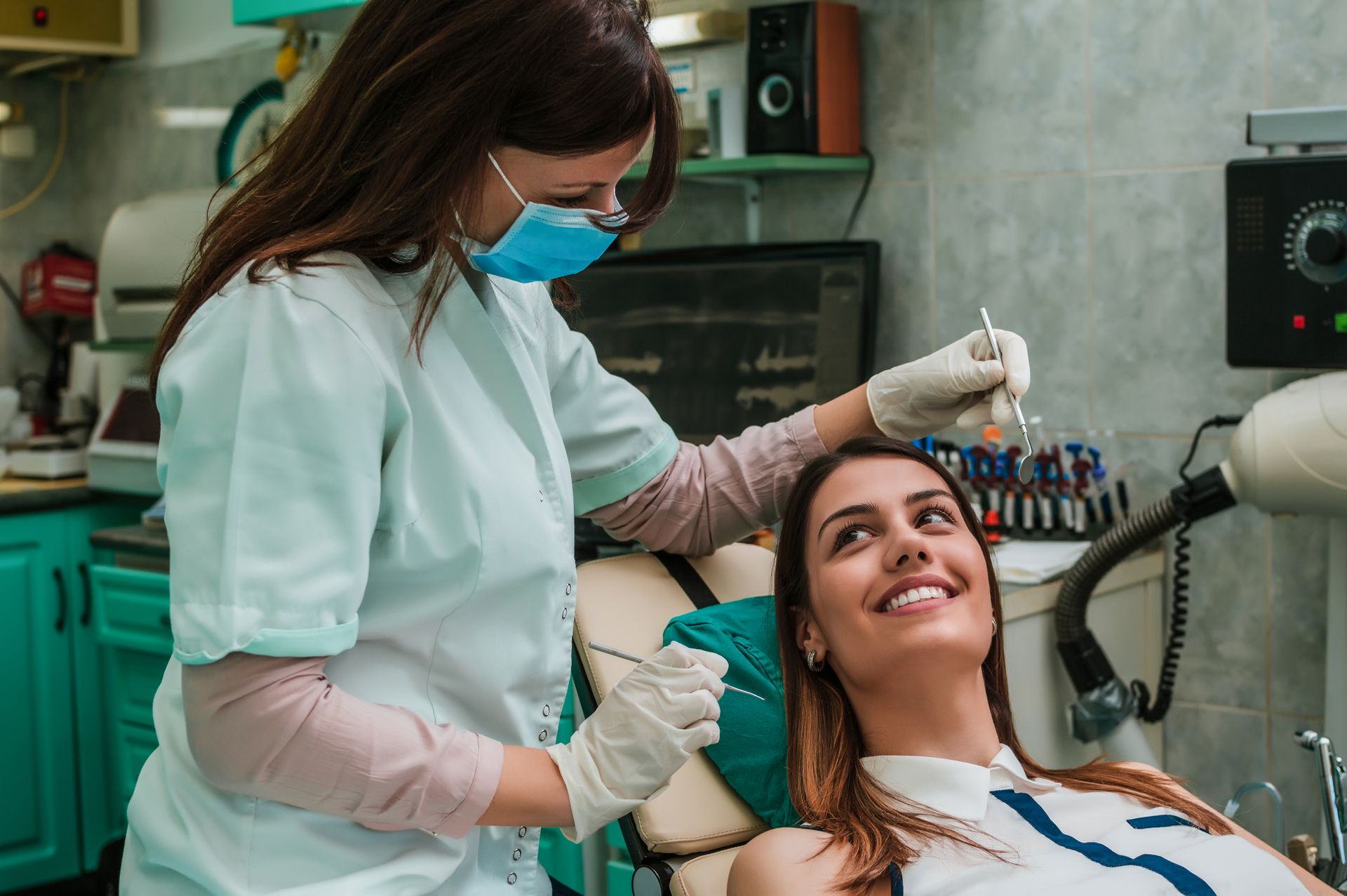Dentista examinando los dientes de un paciente sonriente en un consultorio dental.