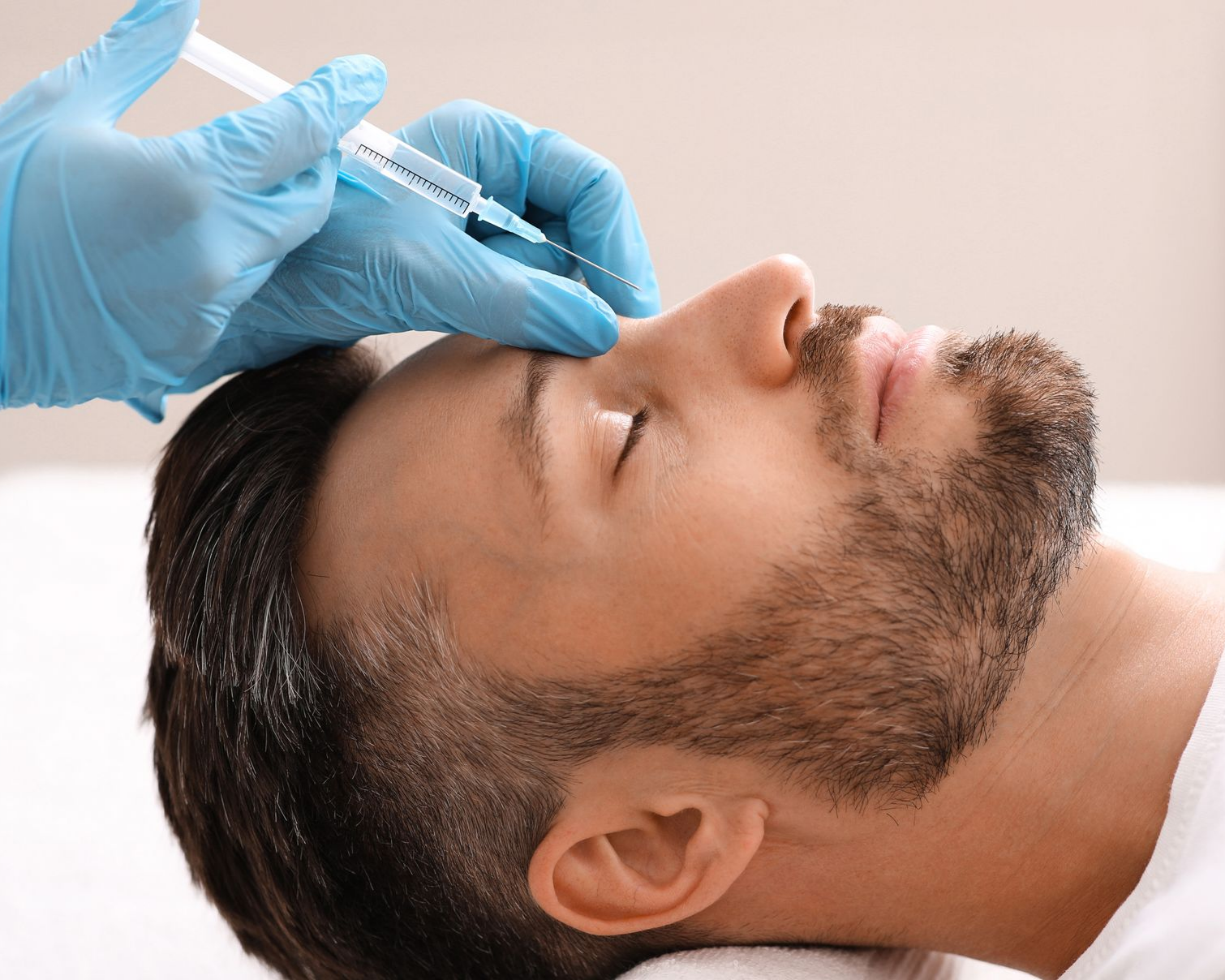 Un homme en position allongée reçoit une injection au front.