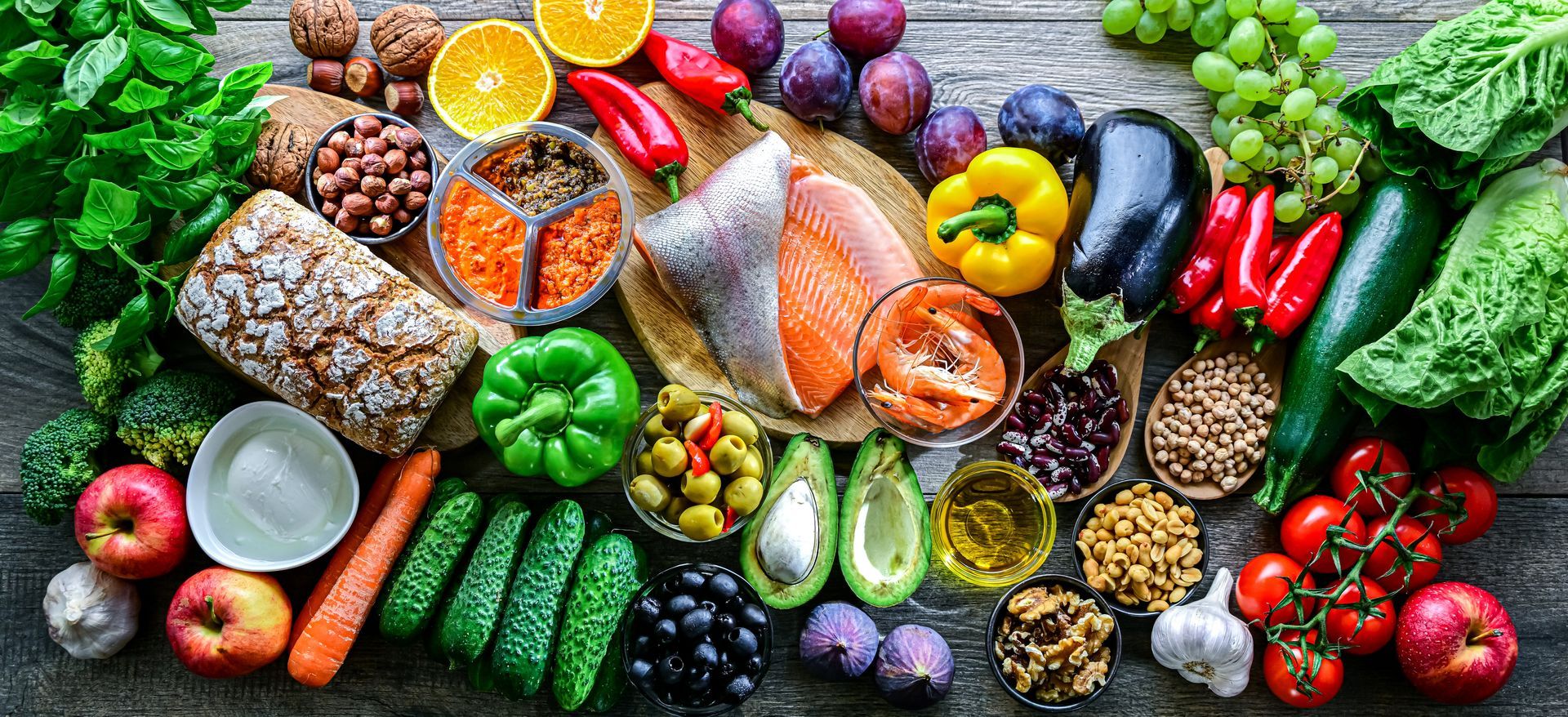 Un assortiment coloré d'aliments sains comprenant des fruits, des légumes, du poisson, des noix et des céréales.